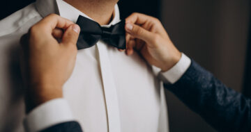 Groom dressing before the wedding ceremony, putting on a bow